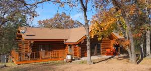 een blokhut in het bos met bomen bij Blue River Inn. Com in Tishomingo
