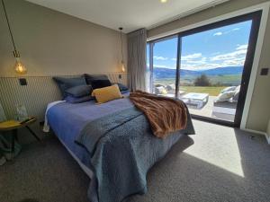 a bedroom with a bed and a large window at Bendigo Ridge - Where Activity is Relaxing in Cromwell