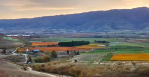 an aerial view of a field with mountains in the background at Bendigo Ridge - Where Activity is Relaxing in Cromwell