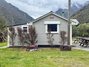 a house with a picnic table in front of it at Rustic, Basic Cosy Alpine Hut, in the middle of the Mountains in Otira