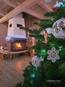 a christmas tree in a living room with a fireplace at Anielskie chaty - domki z widokiem na góry in Sablówka