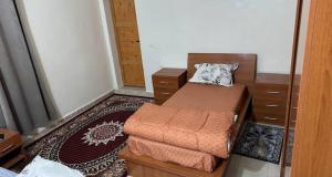 a small bedroom with a bed and a ottoman at Rose du Désert in Atar