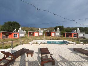 two benches and a pool with houses in the background at Cabañas Nakupenda in Villa Carlos Paz