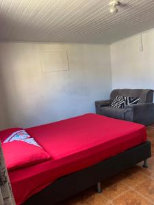 Casa 50 metros da praia mansa في بونتال دو بارانا: سرير احمر في غرفة مع اريكة