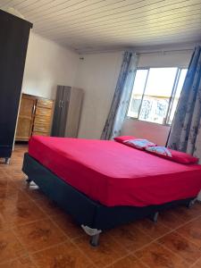 Casa 50 metros da praia mansa في بونتال دو بارانا: غرفة نوم بسرير كبير مع شراشف حمراء ونافذة +صورتان