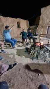 a group of men sitting around a fire at Dar massouada in Gabès