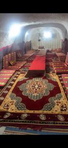 una habitación con filas de alfombras en el suelo en Dar massouada, en Gabès