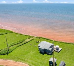 une vue aérienne d'une maison au bord de l'eau dans l'établissement PEI Ocean Front Beach House, à OʼLeary