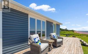 un patio avec deux chaises et une vue sur l'océan dans l'établissement PEI Ocean Front Beach House, à OʼLeary