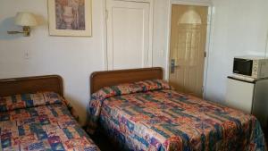 a bedroom with a bed and a microwave on a refrigerator at San Joaquin Motel in Merced