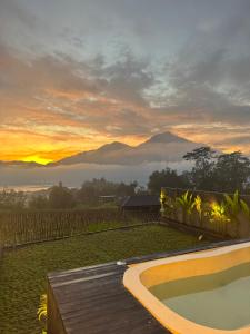 a sunset with a pool and mountains in the background at Aluna Villa Kintamani - Private villa & Hot spring pool in Kubupenlokan