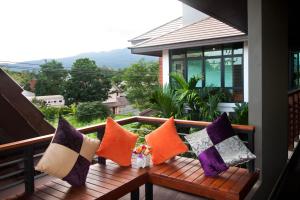 a row of pillows on a wooden bench on a balcony at Burapa Boutique in Chiang Mai