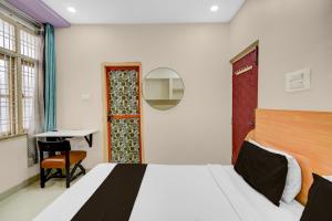 Un dormitorio con una cama, una mesa y un escritorio. en Hotel O De Alphabet Home Stays@NTPC, en Rāmgundam