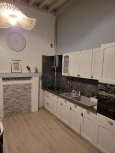 een keuken met witte kasten en een klok aan de muur bij Echappée verte et jacuzzi proche de Paris in Vert-le-Grand