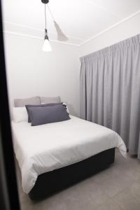 Waterfall Munyaka Estate في ميدراند: غرفة نوم بسرير ذو شراشف بيضاء ومخدات زرقاء