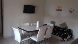 een eettafel met witte stoelen en een televisie bij Complejo Picota III in Mar de Ajó +7 foto's