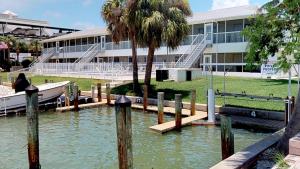 ein Boot, das neben einem Gebäude mit einer Palme angedockt ist in der Unterkunft Driftwood Landing - DWL-1 in Isles of Capri