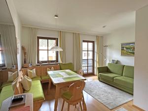 ein Wohnzimmer mit einer grünen Couch und einem Tisch in der Unterkunft Gschwendtnerhof App13 Lincke in Aschau im Chiemgau