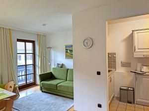 ein Wohnzimmer mit einer grünen Couch und einer Küche in der Unterkunft Gschwendtnerhof App13 Lincke in Aschau im Chiemgau