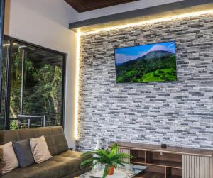 sala de estar con sofá y TV en una pared de ladrillo en Villa Centinela, en Monteverde