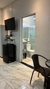 uma sala de estar com televisão e uma mesa e cadeira em SR Casa de férias Astúrias no Guarujá mais 8 fotografias