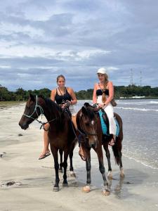 two women are riding horses on the beach at Casa Pelicano in Bocas del Toro