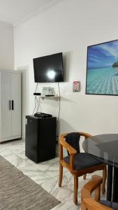 uma sala de estar com uma televisão e uma cadeira em SR Casa de férias Astúrias no Guarujá