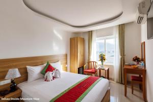 a hotel room with a bed and a desk and a window at Siren Flower Hotel in Nha Trang