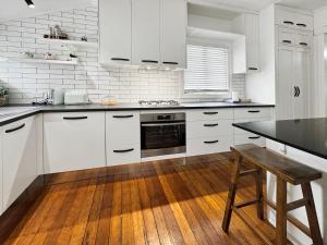 a kitchen with white cabinets and a wooden table at Cosy Cottage 4173 in Brisbane