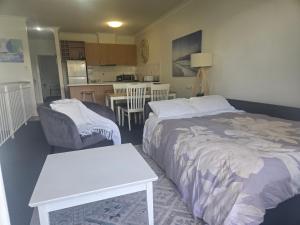 Waterfront Hideaway with Pool, Spa & BBQ Area في ماندورا: غرفة نوم بها سرير وطاولة ومطبخ