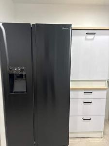 ein schwarzer Kühlschrank in einer Küche mit weißen Schränken. in der Unterkunft Gîtes Vosges, Spa, Sauna & Piscine in Moyenmoutier