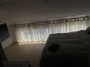 Schlafzimmer mit einem Bett und einem Fenster mit weißen Vorhängen in der Unterkunft Gîtes Vosges, Spa, Sauna & Piscine in Moyenmoutier