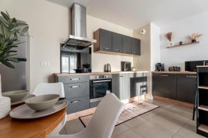 a kitchen with a wooden table and white chairs at Le Magnifique - Grand balcon - Netflix - Grand Marché in Saint-Priest +37 photos