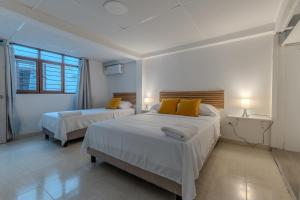 een slaapkamer met twee bedden met gele kussens bij Hotel Stadio Cali in Cali +32 foto's