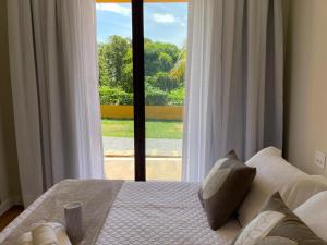 a bedroom with a bed and a large window at Pousada Aloha Buzios in Búzios