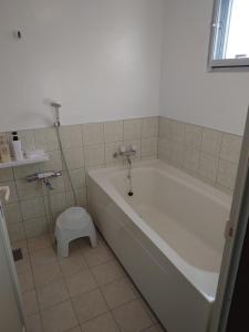 a bathroom with a tub and a toilet in it at ペンションsakuraRIGHT in Motobu