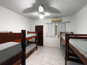 a room with three bunk beds and a ceiling fan at Pousada Adventure in Chapada dos Guimarães