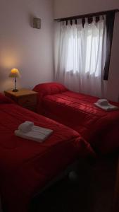 Un dormitorio con dos camas con sábanas rojas y una ventana. en Hotel Lacar, en Mar del Plata