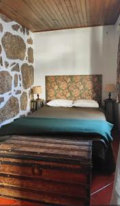 ein Schlafzimmer mit einem Bett mit einer Steinwand in der Unterkunft Casa Na Montanha Da Neve in Seia + 81 Fotos