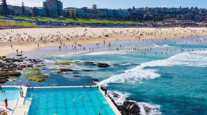 Ein Strand mit einem Haufen Leute im Wasser. in der Unterkunft Bondi Beach Studio with an ocean view in Sydney