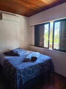 a bedroom with a bed with a blue comforter and two windows at Lorena'Haus in Bombinhas