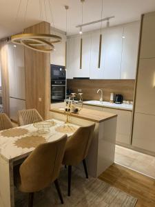 uma cozinha com mesa e cadeiras e uma cozinha com armários brancos em Apartman VIS em Arandjelovac
