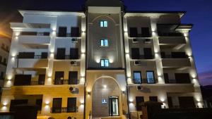 um edifício branco alto com luzes em Apartman VIS em Arandjelovac