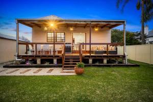 a small house with a large deck in a yard at Hunter Valley Spa Stay in Cessnock
