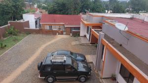 a black car parked on a dirt road next to buildings at Palm Suites Unit3 in Mbale +2 photos