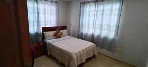 a small bedroom with a bed with a striped blanket at Purple Springs Elmina #1 in Esamang