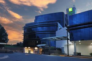 メキシコシティにあるホリデイ イン ホテル ＆ スイーツ メキシコ メディカ スールの看板が目の前にある大きなガラス張りの建物