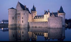 a castle sitting in the water at night at Le gîte du château in Saint-Père-sur-Loire