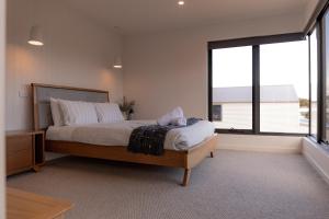 een slaapkamer met een bed en een groot raam bij House Peron - Bayside Luxury in St Helens