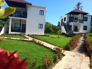 a white house with a yard with flowers at Villas Reynoso, Near La Playita Beach in Las Galeras Samaná in Las Galeras